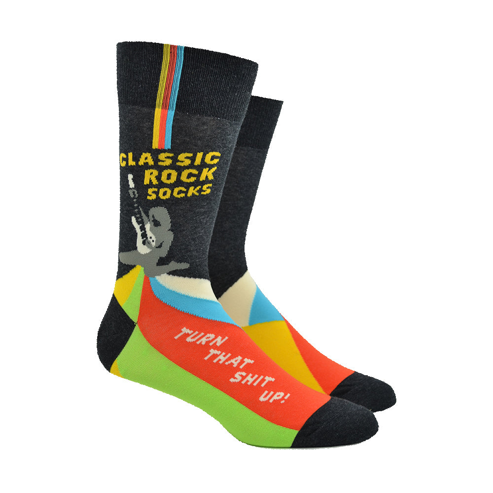 Shown on a leg form, a pair of Blue Q cotton men’s crew socks with dark gray background, electric guitar, orange/green/blue accents and the words “classic rock socks” on the calf, as well as “turn that shit up!” on the foot