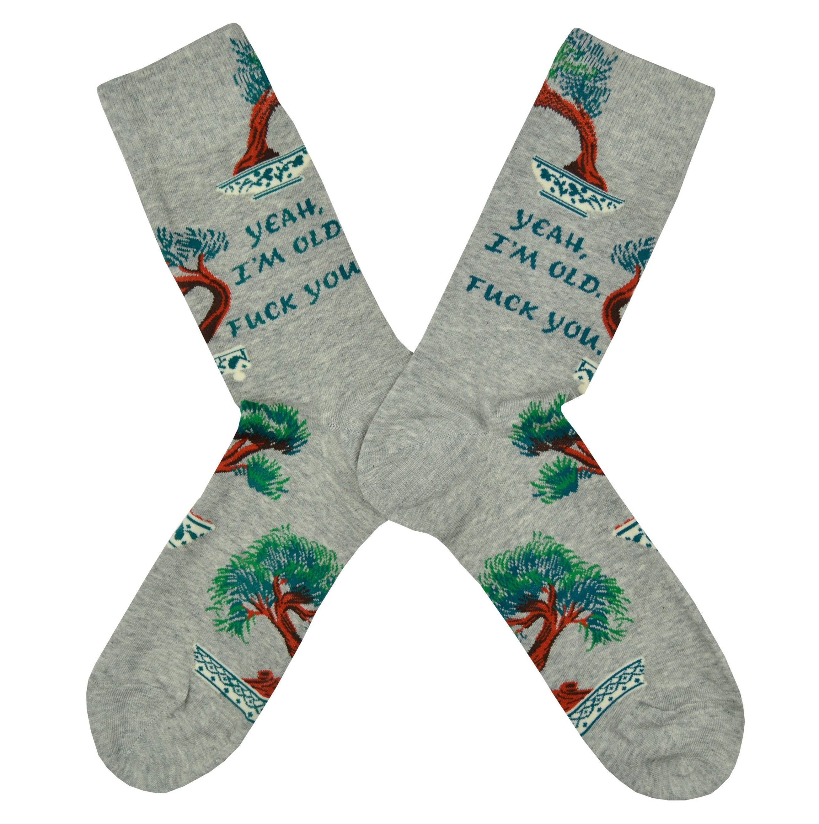 Shown in a flatlay, a pair of Blue Q brand men's cotton crew sock in grey with bonsai trees scattered around the sock. The text on the leg of the sock reads, 