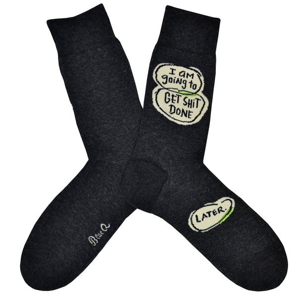 These dark gray cotton funny men's crew socks by the brand Blue Q have word bubbles with the words "I am going to get shit done" on the leg and another word bubble with the word "later" on the foot.