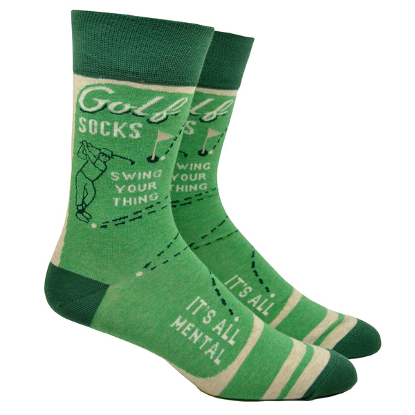 Shown on a leg form, a pair of Blue Q green cotton men’s crew socks with a man swinging a golf club and the words “Golf Socks,” “Swing Your Thing,” and “It’s All Mental”