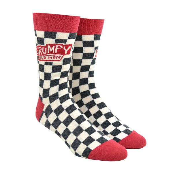 Shown on a leg form, a pair of Blue Q gray/white checkered cotton men’s crew socks with warm brown cuff/heel/toe and the text “Grumpy Old Man”