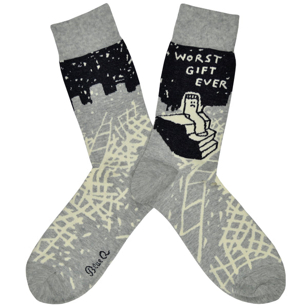 Shown in a flaylay, a pair of Blue Q brand men's cotton crew socks in grey and black with an abstract crisscross design along the foot and a sad sock sitting on stairs on the leg. The text on the sock reads, "Worst Gift Ever" along the top.