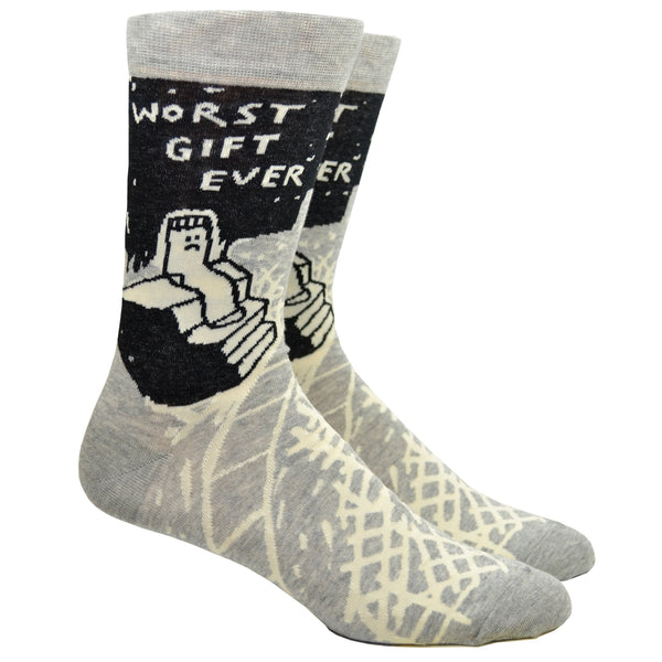 Shown on leg forms, a pair of Blue Q brand men's cotton crew socks in grey and black with an abstract crisscross design along the foot and a sad sock sitting on stairs on the leg. The text on the sock reads, "Worst Gift Ever" along the top.