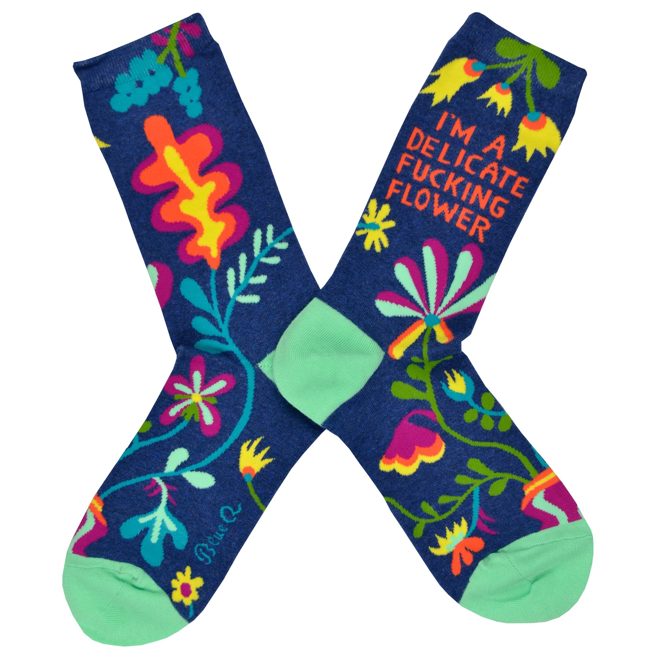 Shown in a flatlay, a pair of Blue Q brand women's nylon and combed cotton socks in navy blue with a teal heel and toe. These socks feature an all over motif of psychedelic inspired flowers and the phrase 