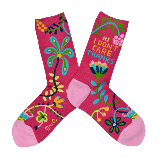 Shown in a flatlay, a pair of women's Blue Q brand combed cotton crew socks in hot pink with a light pink heel and toe. This sock features and abstract floral design with the phrase " HI I DON'T CARE THANKS" on the leg.