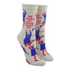 Shown on a leg form, these cream cotton women's novelty crew socks by the brand Blue Q feature pink women wearing purple clothes dancing in different styles and the quote "Me When My Song Comes On".