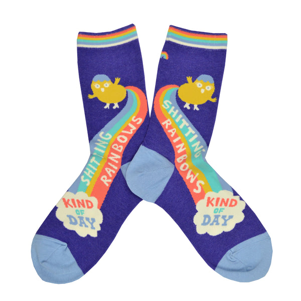 A cute cartoonish figure is shown on a purple cotton Blue Q woman's crew sock farting a rainbow with the words "Shitting rainbow kind of day" written along the rainbow fart.