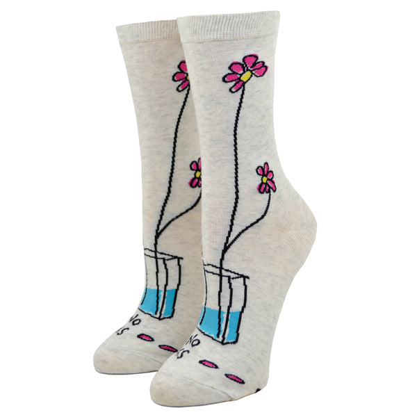 Two dainty flowers are seen poking out of small vase on the backside of a "Take no shit, give no fucks" blue q women's cotton crew sock.