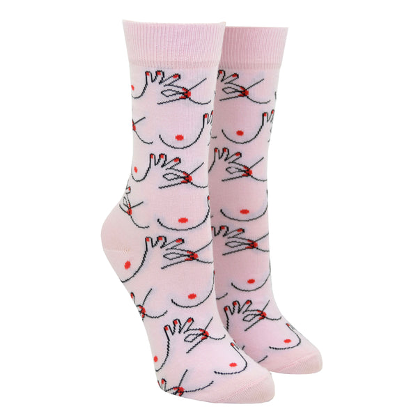 Shown on a leg form, these pink cotton women's crew socks by the brand Coucou Suzette feature bare breasts and a hand pinching one of the nipples.