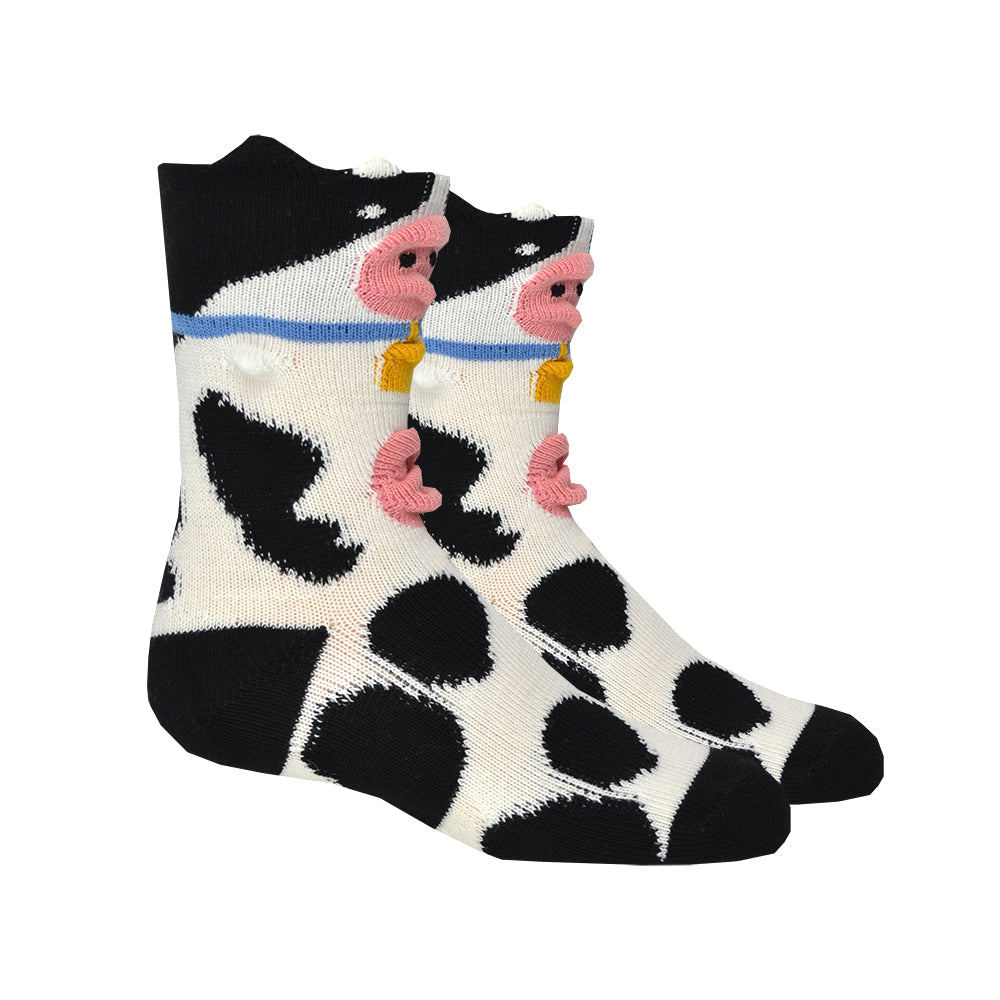 Shown on a leg form, these kids cotton crew length cow socks by the brand Foot Traffic feature 3D udders and noses.
