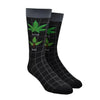 Shown on a foot form, a pair of Foot Traffic black cotton men's crew socks with a pot leaf titled in text “Good Weed” and a poison oak plant titled in text “Bad Weed”