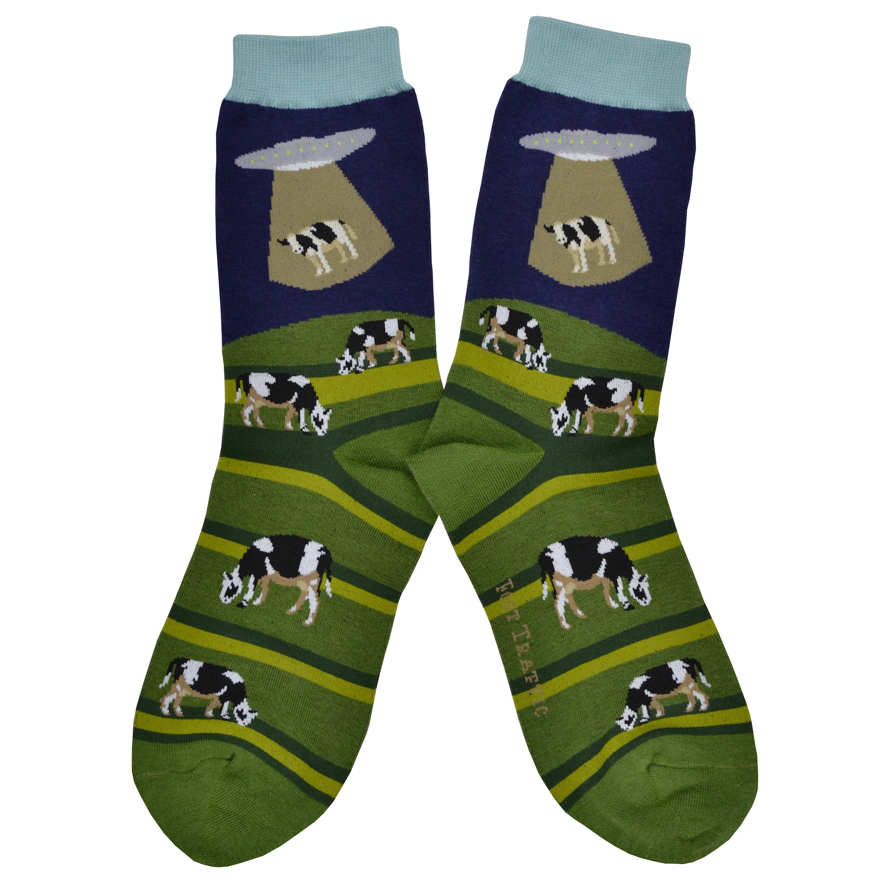 These blue and green cotton women's crew socks with a light blue cuff by the brand Foot Traffic feature an alien spaceship beaming up a cow that was grazing in a field.