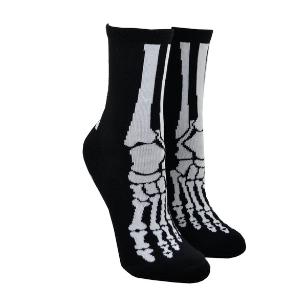 Shown on women's leg forms, a pair of Foot Traffic brand, women's cotton crew socks in black. These socks feature a skeletal foot design on the front and little rubber grips on the foot of the sock.