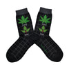 Shown in a flatlay, a pair of women's Foot Traffic cotton crew socks in black with a grey cuff and a grey grid pattern. The leg of the sock has a marijuana leaf with the word "Good" under it and a poison ivy leaf with the word "Bad" underneath.