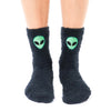 A pair of black fuzzy socks with an embroidered green alien face on the front of the calf.