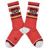 Shown in a flatlay, a pair of cotton crew length unisex Gumball Poodle brand socks in red with a sparkly silver toe and heel. The leg of the sock features, black, sparkly silver, and yellow stripes with the phrase, "100% That Bitch" along the cuff.