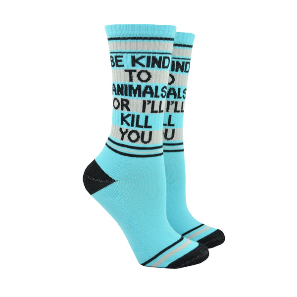 Shown on leg forms, a pair of unisex cotton crew Gumball Poodle brand socks in light blue with black, blue, and grey stripes around the leg and cuff. The heel and toe are black and the leg of the sock reads in black font, BE KIND TO ANIMALS OR I'LL KILL YOU".