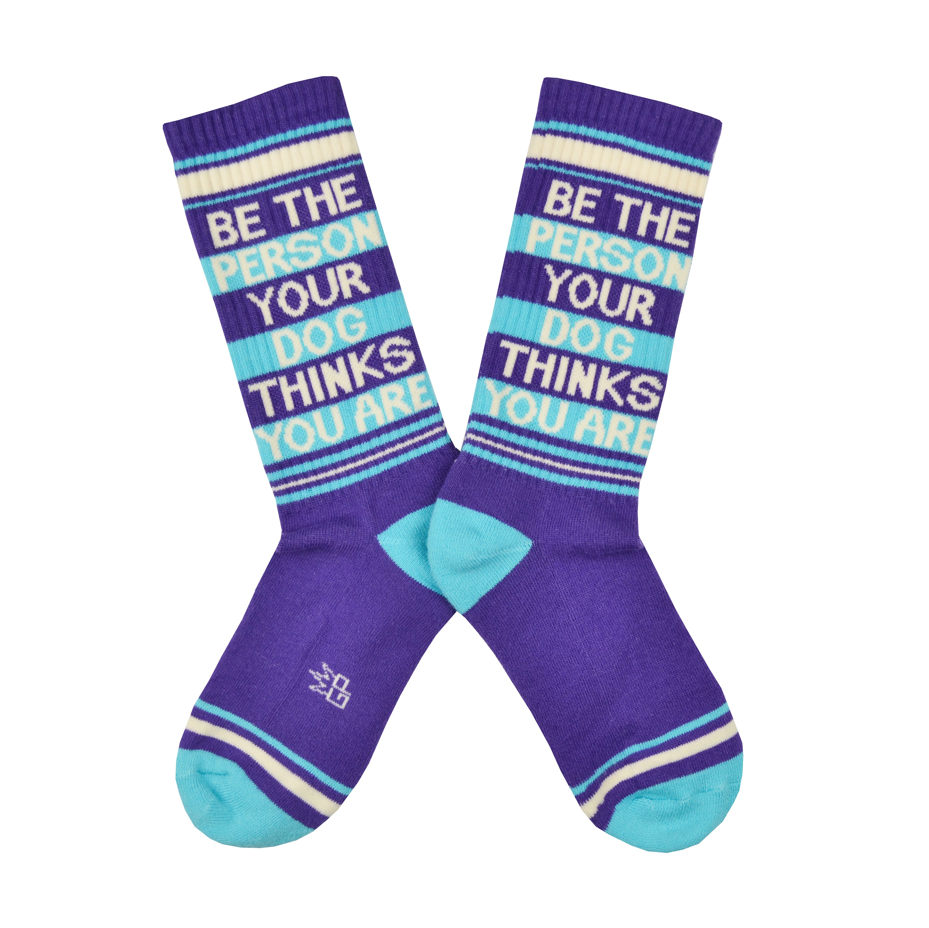 Shown in a flatlay, a pair of Gumball Poodle brand unisex cotton crew sock in purple with cream and blue stripes around the leg and a blue heel and toe. On the side of the sock in cream lettering it says, 