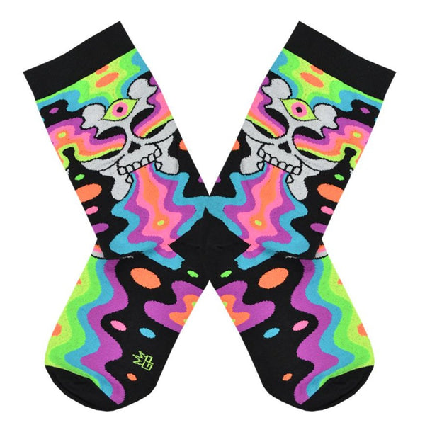 Shown in a flatlay, a pair of Gumball Poodle black cotton crew socks with illustrative skull spewing neon rainbow psychedelic spirals all down the foot