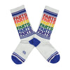 Shown in a flatlay, a pair of Gumball Poodle white cotton crew socks with blue toe/heel and rainbow repeating “Farts” text