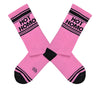 Shown in a flatlay, a pair of pink cotton Gumball Poodle brand unisex crew socks with black striped toe and cuff. These socks feature the words, "HOT HOMO" on the leg in black.