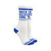 Shown on legforms, a pair of Gumball Poodle brand unisex cotton crew sock in white with a blue striped cuff/heel/toe and the words, "NICE JEWISH GIRL" on the leg.
