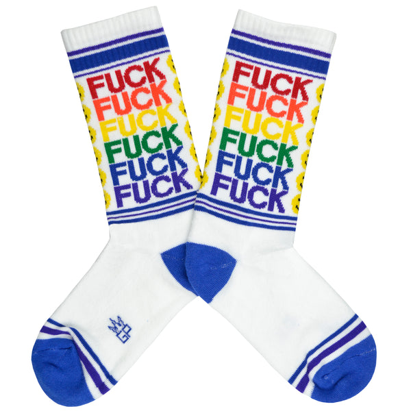 These white cotton unisex crew socks with a blue toe and striped cuff by the brand Gumball Poodle feature the words "FUCK YOU" in rainbow colors repeated down the leg and emoji smiley faces running down the front.