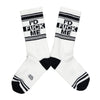 Shown in a flatlay, a pair of white cotton Gumball Poodle brand unisex crew socks with black and white striped heel/toe/cuff featuring the words, "I'D FUCK ME" on the leg.