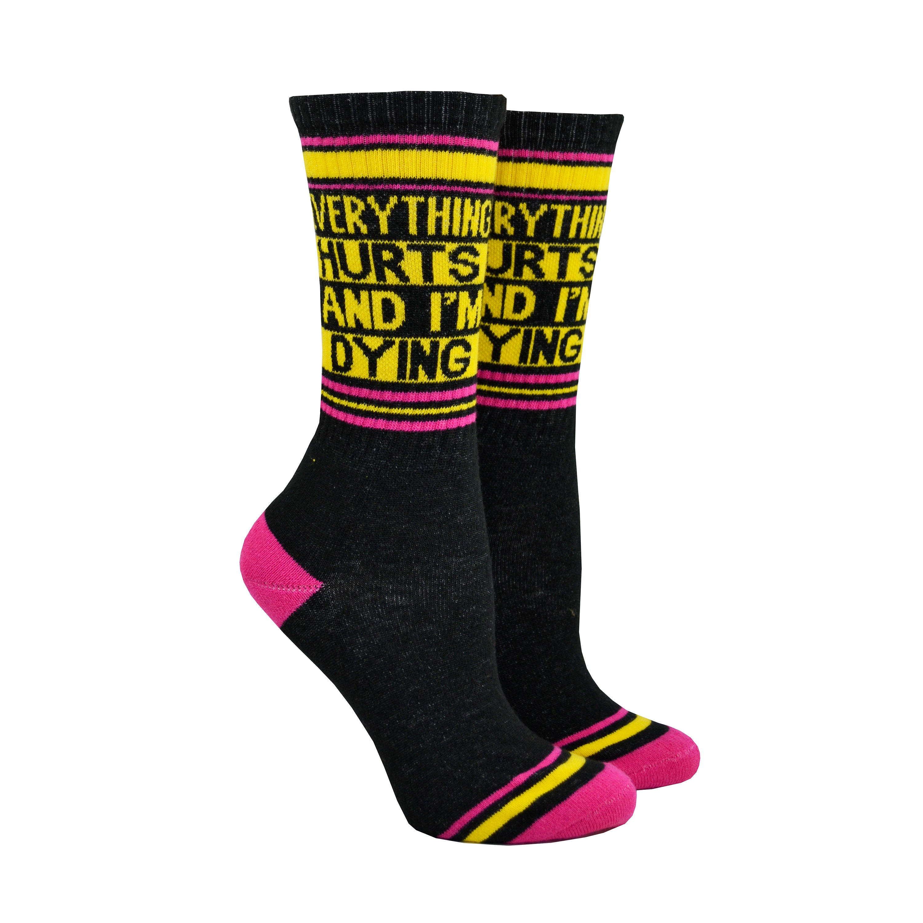 Shown on a foot mold, a pair of Gumball Poodle black cotton crew socks with pink toe/heel and yellow “Everything Hurts and I’m Dying” text