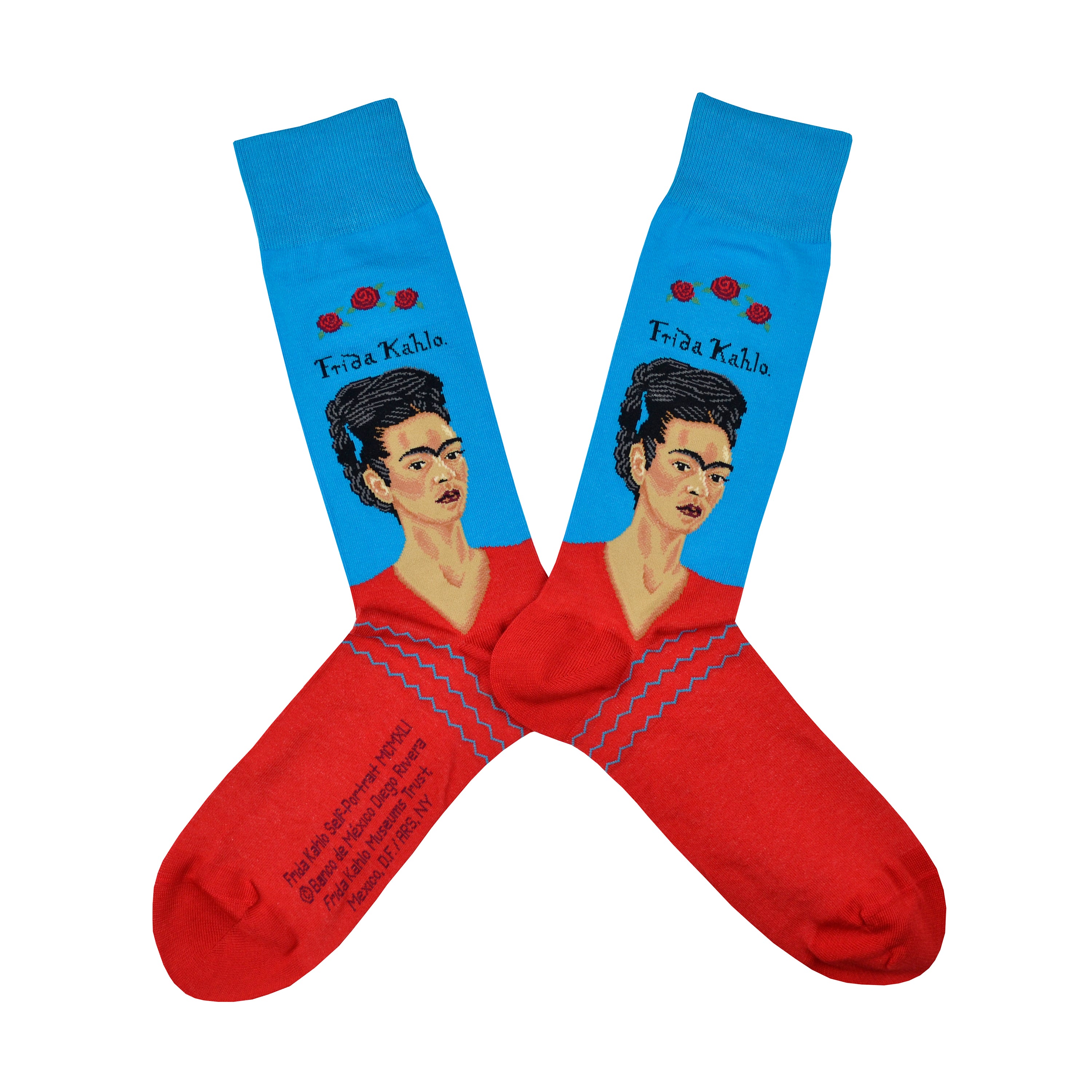 Shown in a flatlay, a pair of Hot Sox cotton men’s crew socks with the artist Frida Kahlo in a red shirt with a blue background and her name in text above her