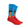 Shown on a leg form, a pair of Hot Sox cotton men’s crew socks with the artist Frida Kahlo in a red shirt with a blue background and her name in text above her