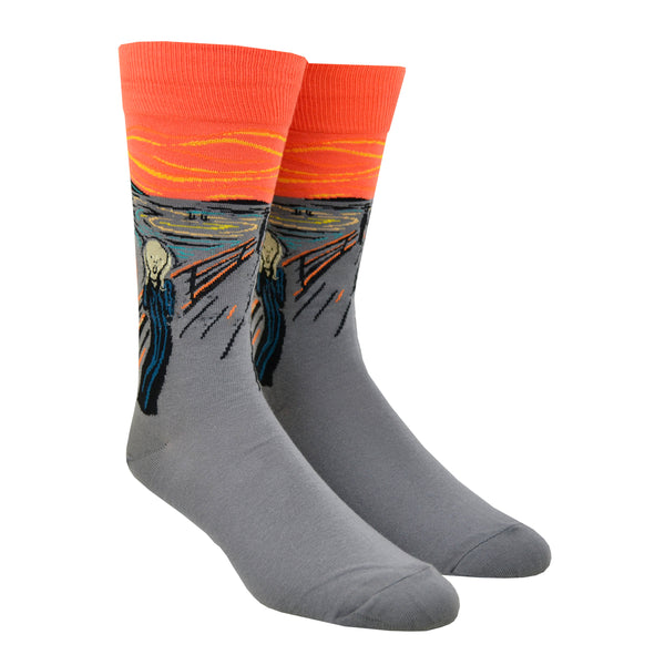 Shown on a leg form, a pair of Hot Sox cotton men’s crew socks with orange background and the artist Edvard Munch’s abstract painting of a screaming figure on a bridge