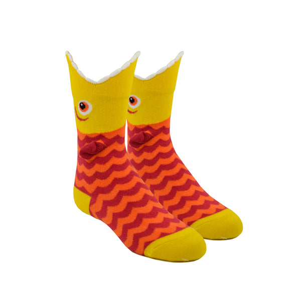 Shown on leg forms, a pair of K.Bell brand kids cotton crew socks with a yellow heel, toe, and cuff and an orange and red sock. The top of the sock features a mouth shaped top with a cartoon fish eye and the body of the sock is red and orange zig zag.
