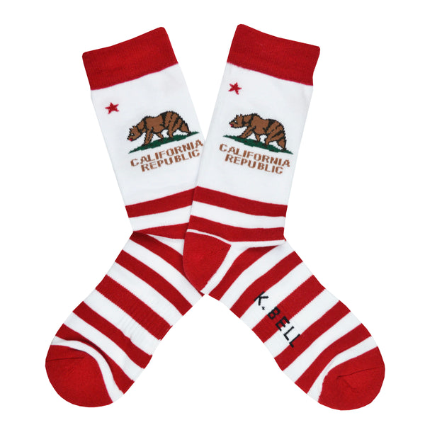 Shown in a flatlay, a pair of K. Bell’s white cotton men’s crew socks with red stripes/cuff/heel/toe and California flag print