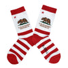 Shown in a flatlay, a pair of K. Bell white cotton women's crew socks with red stripes, brown bear and “California Republic” text, reminiscent of the California flag