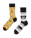 flatlay of a pair of mistmatched crew length socks, one yellow with a pattern of raccoons, trash cans, apple cores, fish bones and raccoon faces, the other shaes of black and gray stripes with a couple raccoons appearing to crawl out of the stripes