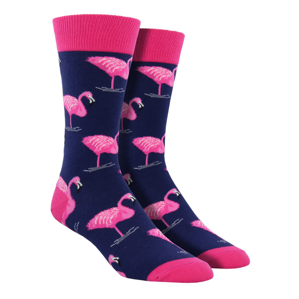 Shown on a foot form, a pair of Socksmith's navy cotton men's crew socks with pink flamingo all over pattern
