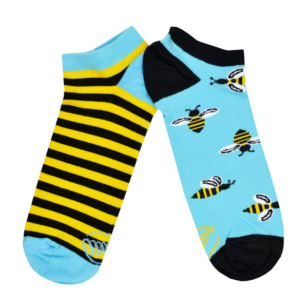 Shown in a flatlay, a pair of unisex mismatched Many Mornings brand cotton ankle socks. One sock is blue with a black heel/toe/cuff and black and yellow bee motif all over the sock. The second sock is a black and yellow striped sock with blue heel/toe/cuff.
