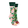 Shown on a leg form, these pink cotton mis-matched women's crew socks with a green cuff by the brand Many Mornings feature beautiful potted Monstera plants and succulents all over the foot and leg.
