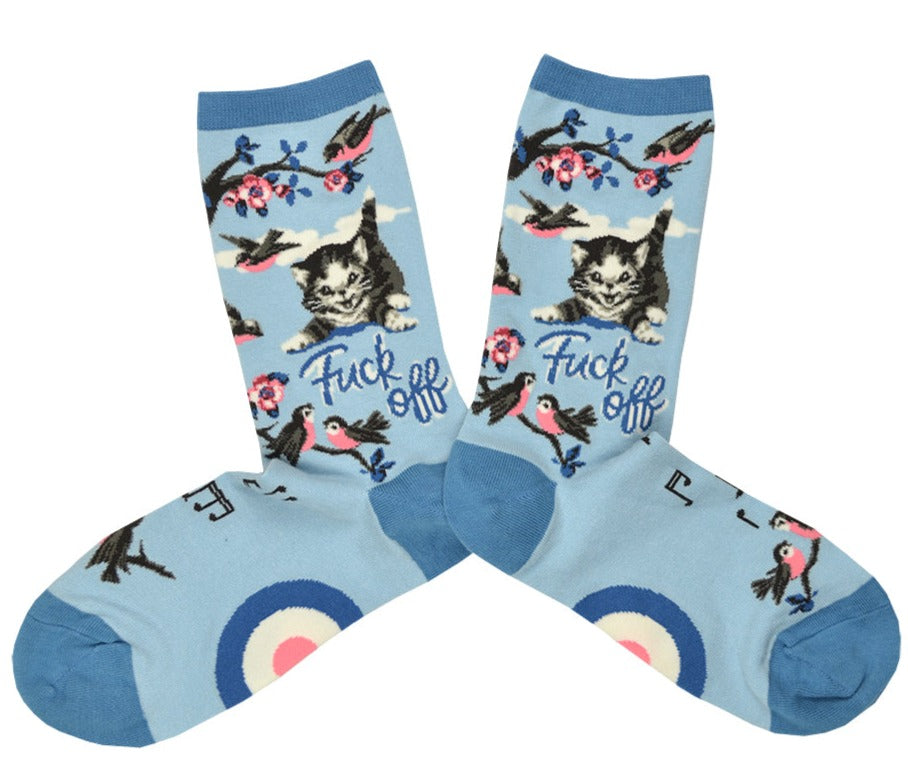Shown in a flatlay, a pair of Mod Socks brand women's cotton crew socks in blue with a dark blue heel, toe, and cuff. The sock features a flowering branch with birds on the leg and foot and a meowing cat on the leg with the words 