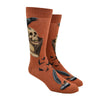 Shown on a foot form, a pair of Mod Socks’ warm brown cotton men's crew socks with a stack of books, skull, and raven