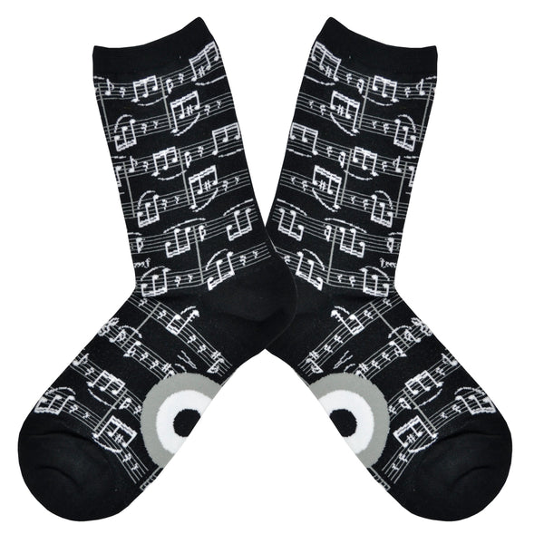 Shown in a flatlay, a pair of Mod Socks’ black cotton women's crew socks with white print of small sheet music and musical notes