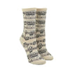 Shown on a foot form, a pair of Mod Socks’ white cotton women's crew socks with black print of small sheet music and musical notes
