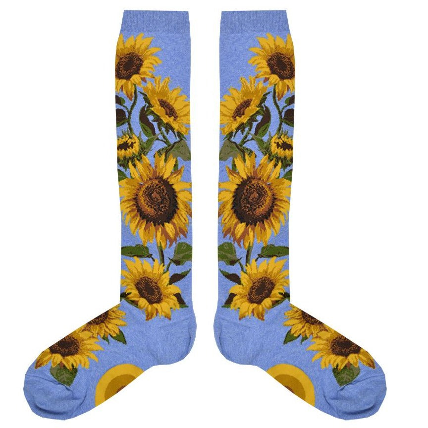 A pair of sky blue knee high socks with realistic sunflowers going from the foot to the top of the sock. 