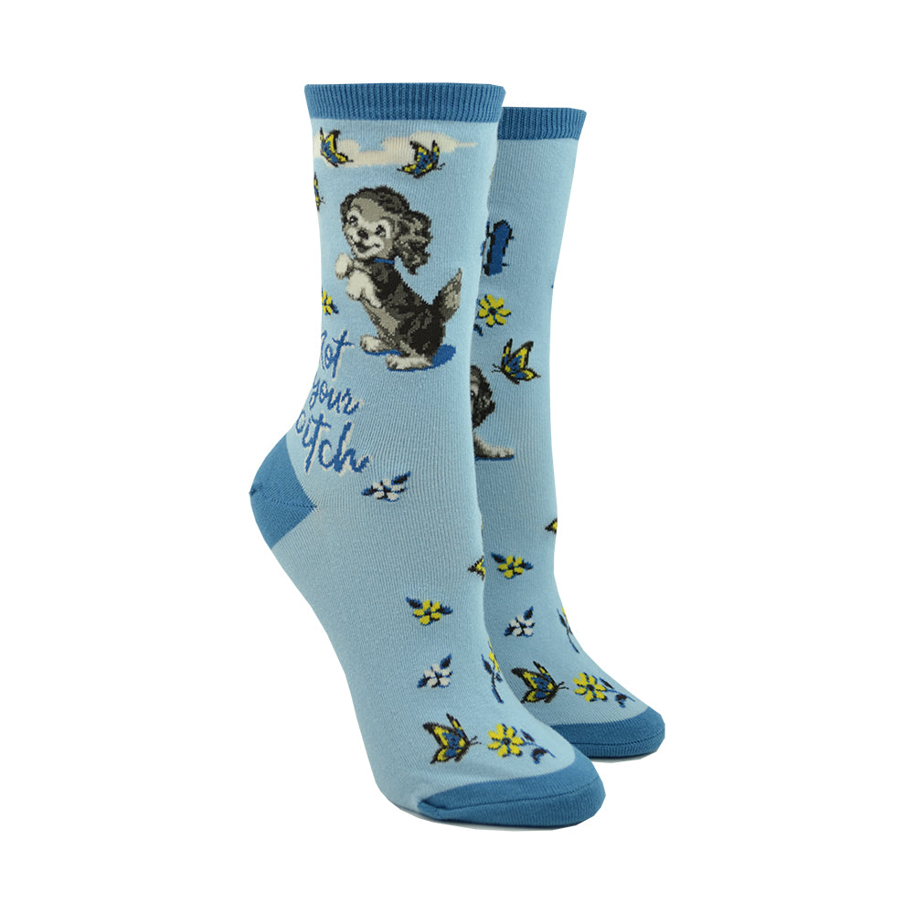 Shown on a leg form, these blue cotton women's crew socks feature an adorable puppy sweetly smiling with dainty yellow flowers and butterflies throughout and the text 