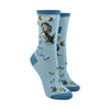 Shown on a leg form, these blue cotton women's crew socks feature an adorable puppy sweetly smiling with dainty yellow flowers and butterflies throughout and the text "Not Your Bitch" written on the leg.