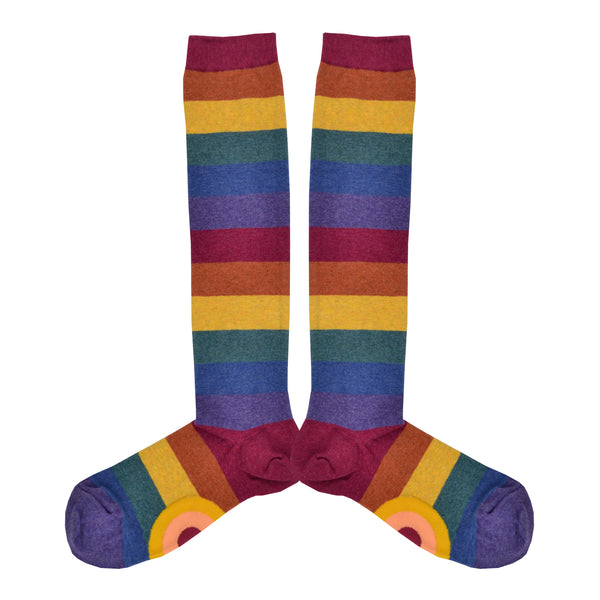 Shown in a flatlay, a pair of women's knee high cotton socks by ModSocks. These socks feature a muted rainbow stripe in red, burnt orange, matte gold, emerald green, dark blue, and purple.