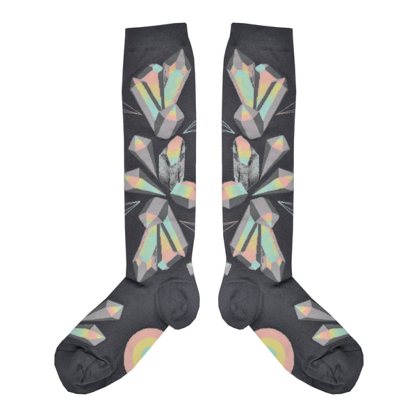 Shown in a flatlay, a pair of ModSocks brand women's cotton knee highs. These grey socks feature an all over design of pastel blue, green, pink, and yellow crystals.