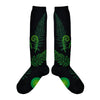 Shown in a flatlay, a pair of women's Mod Socks brand knee high cotton socks in black with green ferns and fiddleheads from the foot to the cuff.