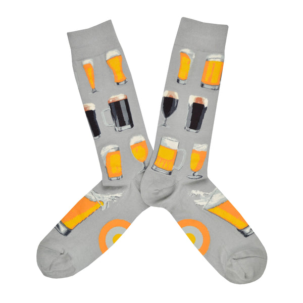 Shown in a flatlay, a pair of Mod Socks’ gray cotton men's crew socks with various steins of foamy beer